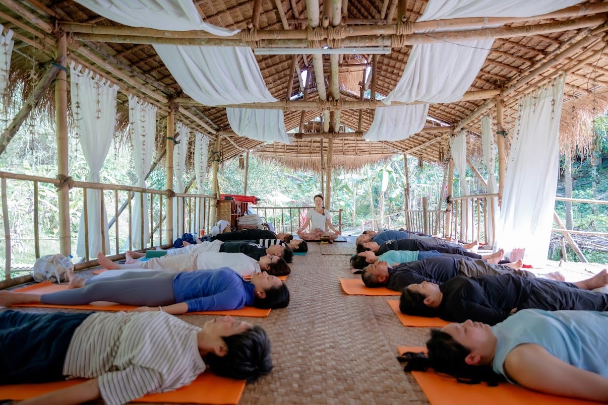 ช่วงพักผ่อนใต้ศาลากลางแจ้ง ผู้เรียนนอน savasana ครูนั่งกลางวง